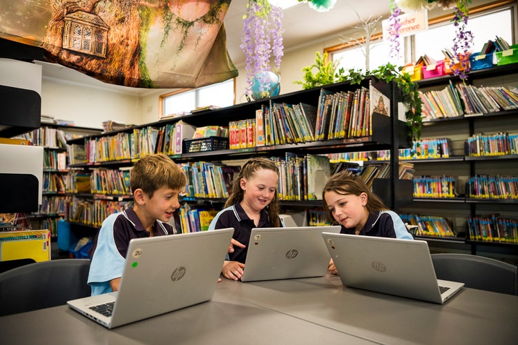 Three students utilising the resources in the colourful school library.