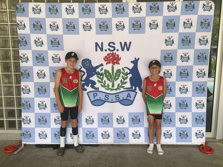 2 students in front of the NSW PSSA banner, representing our region at the State Athletics carnival.