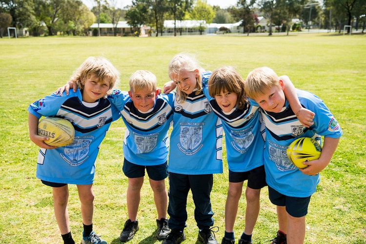 Five boys arm in arm, enjoying playing Rugby League.