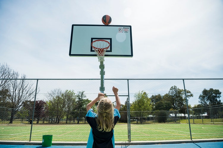 A young boy takes a shot at the basketball ring.
