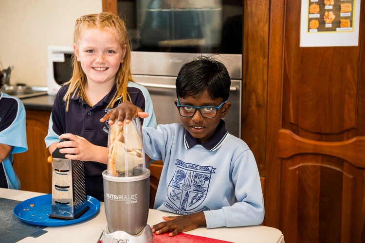 Two children enjoying cooking in the school kitchen.