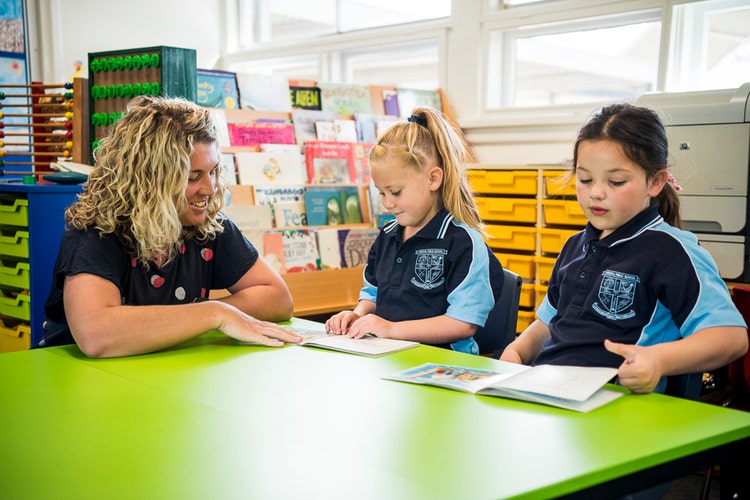 A teacher reading to 2 students.